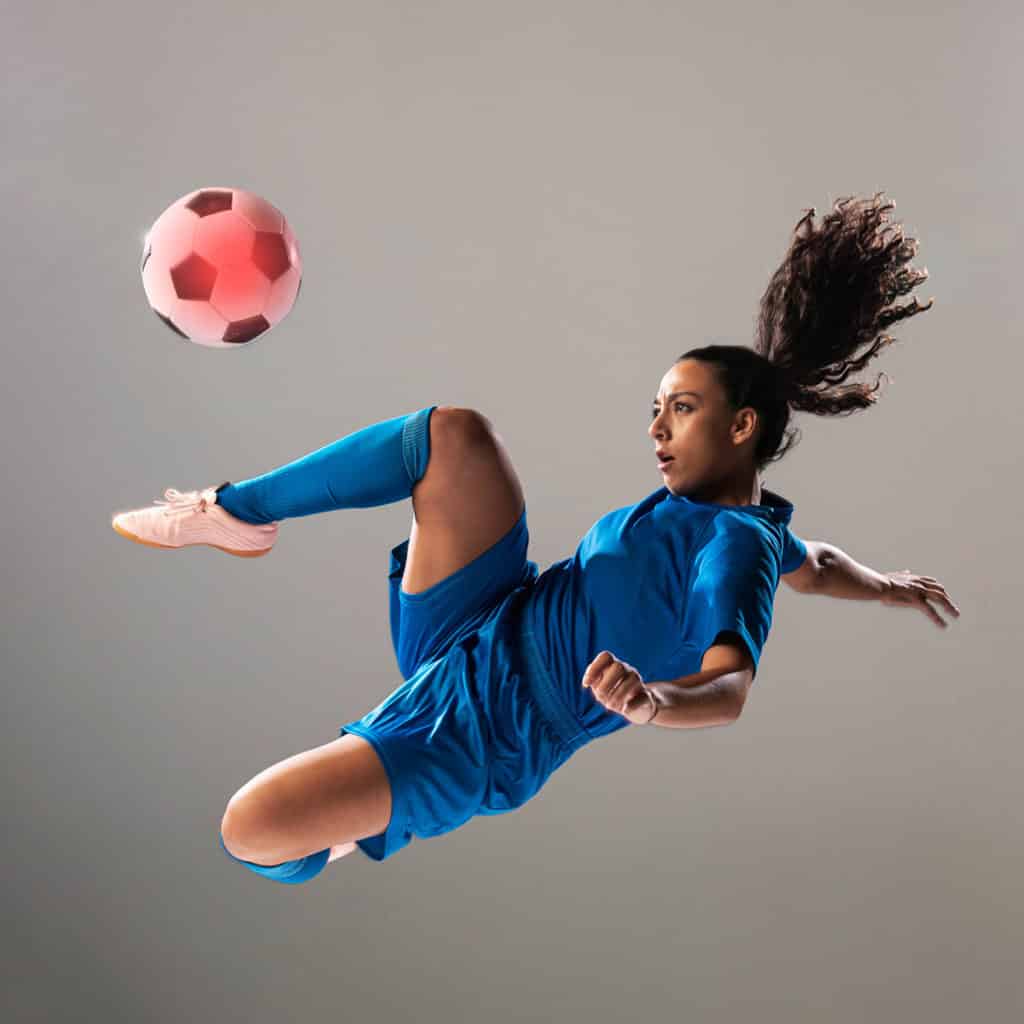 woman executing a bicycle kick on a soccer ball